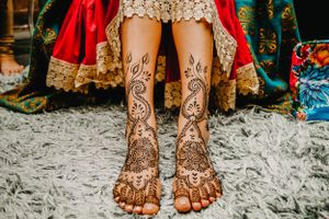 Detailed henna designs on feet adorned with traditional Indian wedding jewelry.