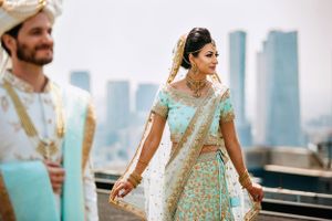 Wedding couple dances and celebrates with city skyline visible through large windows.
