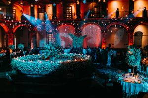 Elegant wedding reception venue with dramatic lighting and table settings in blue and orange tones.