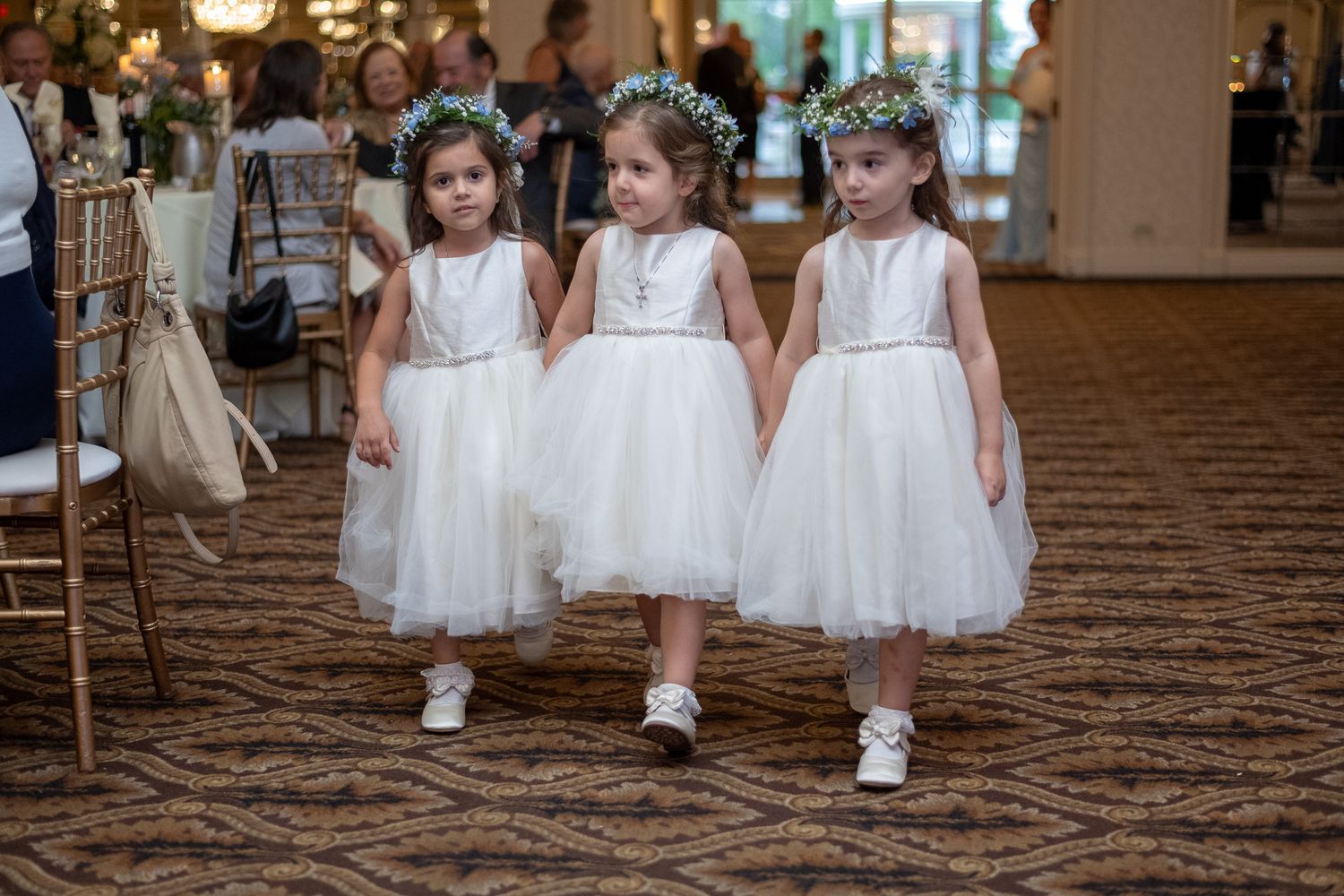 Black and white outdoor wedding ceremony with flower girls in tulle dresses and seated guests on a sunny patio.