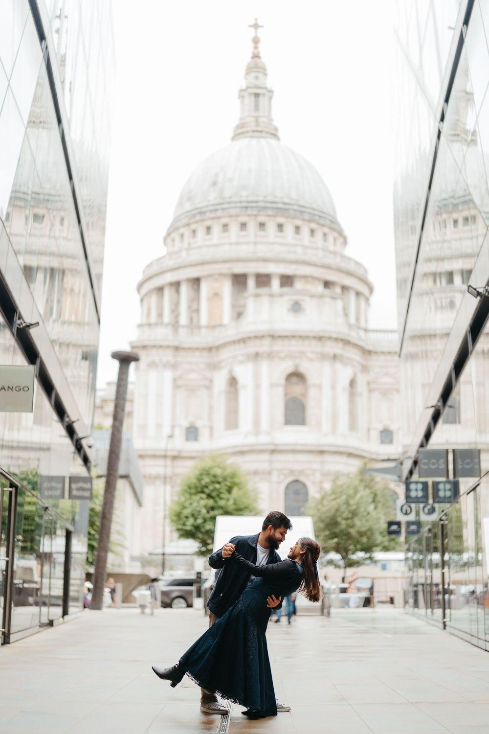 Couple dancing romantically in front of St. Paul's Cathedral in London, woman in elegant navy gown.
