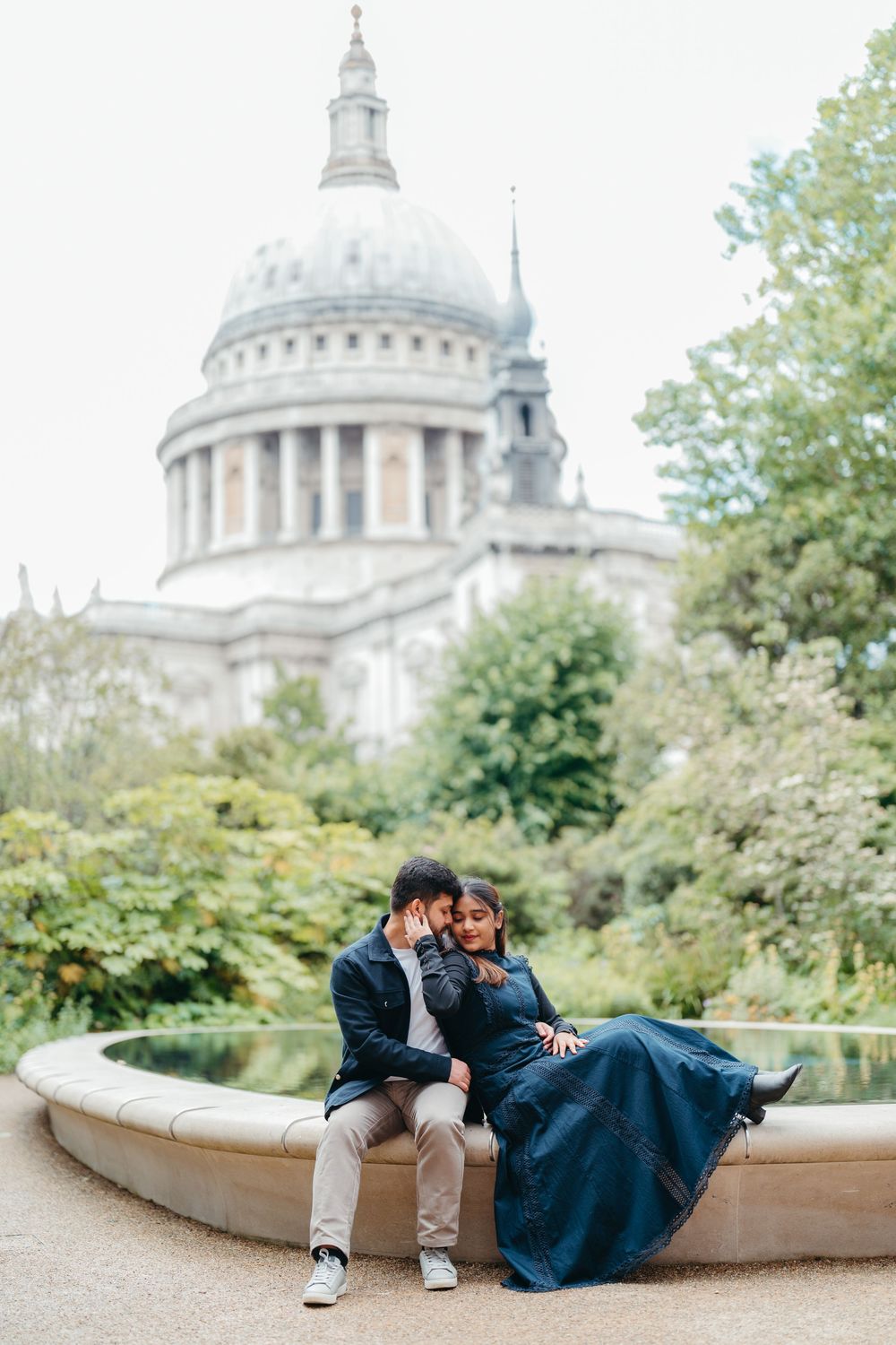 Couple sitting embracing by a fountain with St Pauls Cathedral in background.