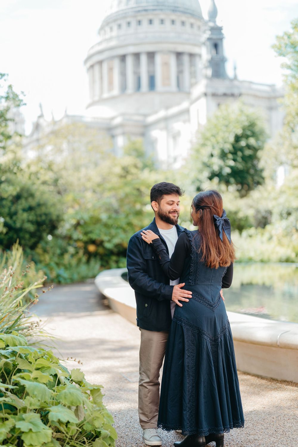 Couple embracing in a garden path with St. Paul's Cathedral dome visible in the background, London.