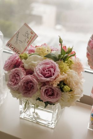 Elegant congratulations floral arrangement with pink roses and peonies in a glass vase.