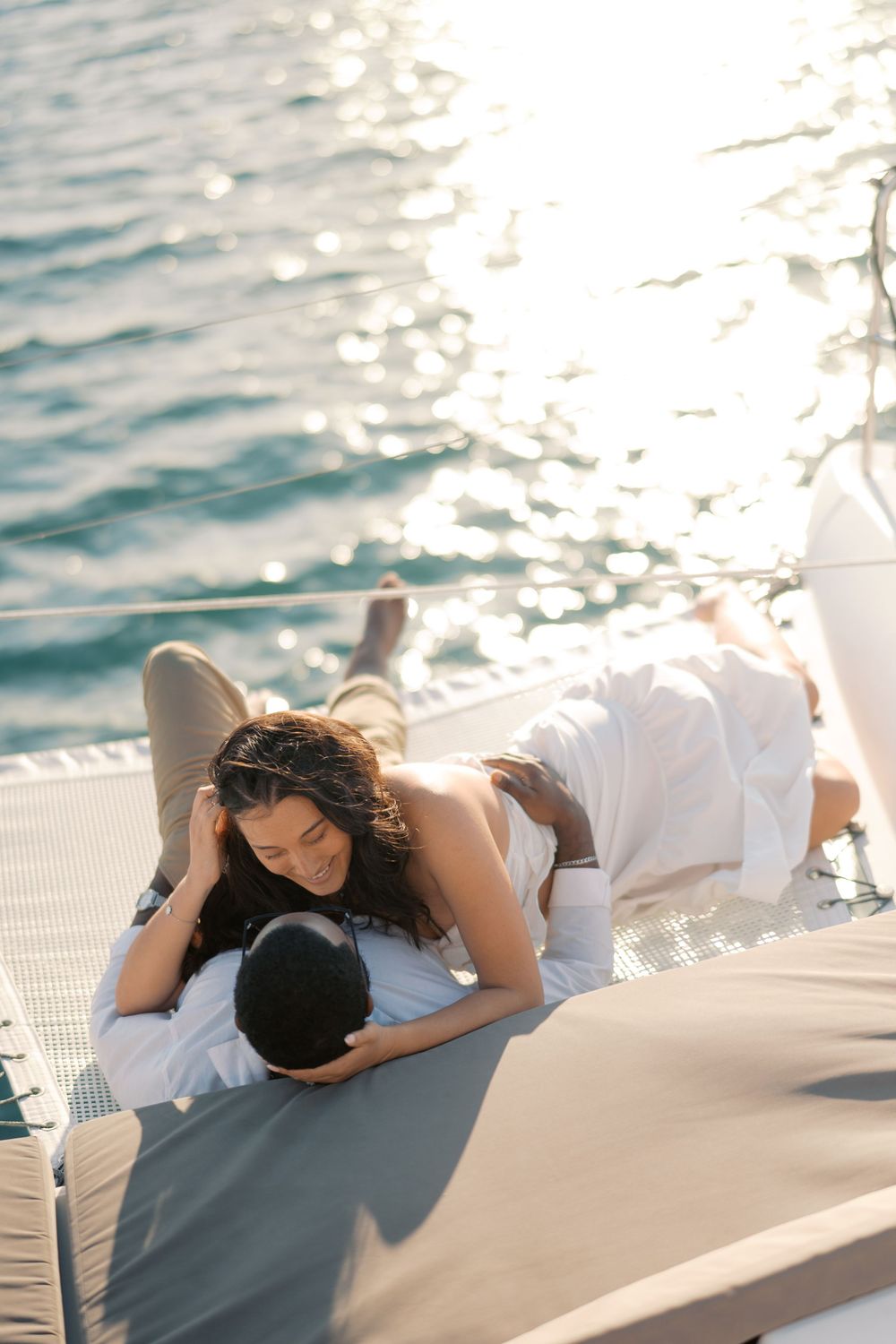 Romantic couple relaxing together on a luxury yacht deck with sparkling ocean water in the background.