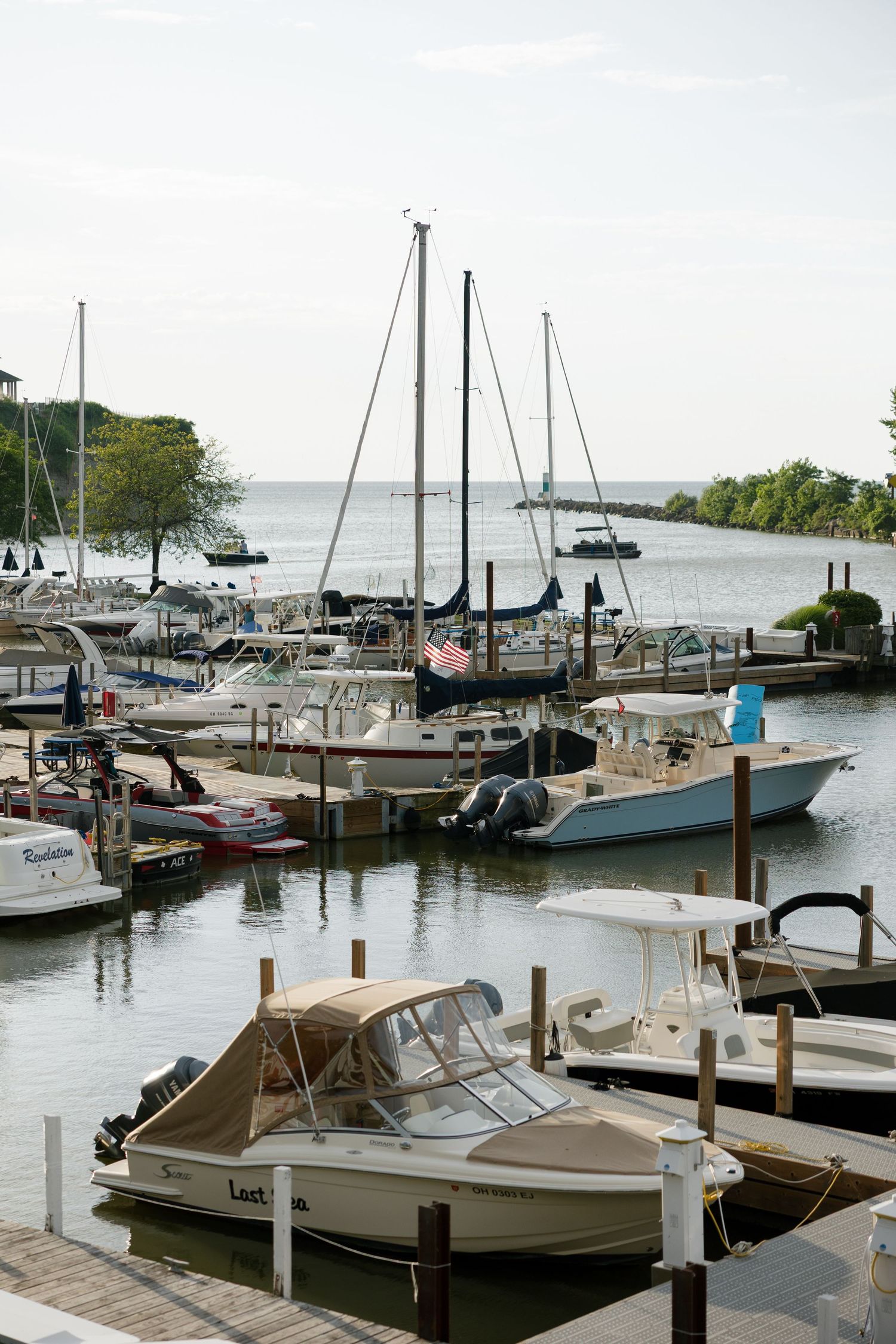 Scenic marina with sailboats and motorboats docked on calm water at a peaceful harbor.