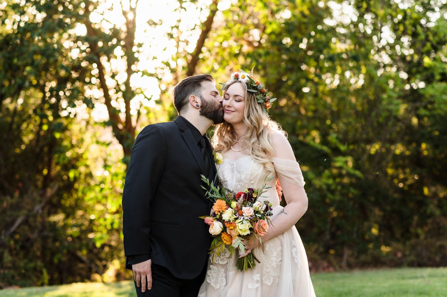 Joyful bride and groom lifted by guests at wedding reception with bubbles and string lights.