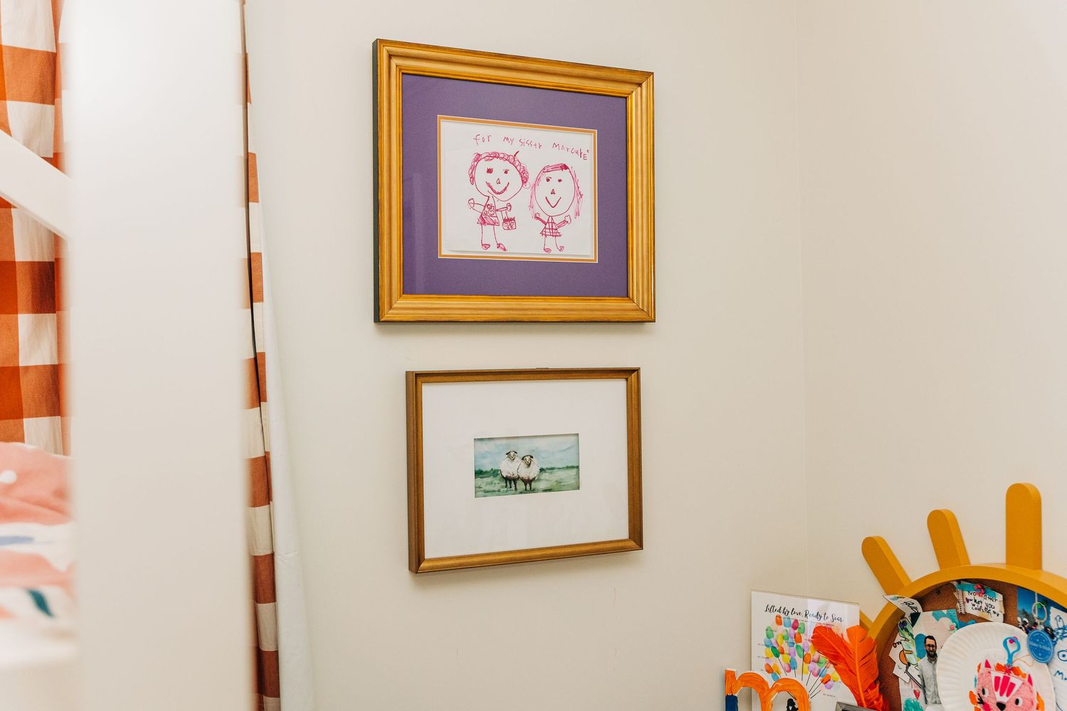 A colorful bedroom wall decorated with orange and white striped poles and framed artwork displays.