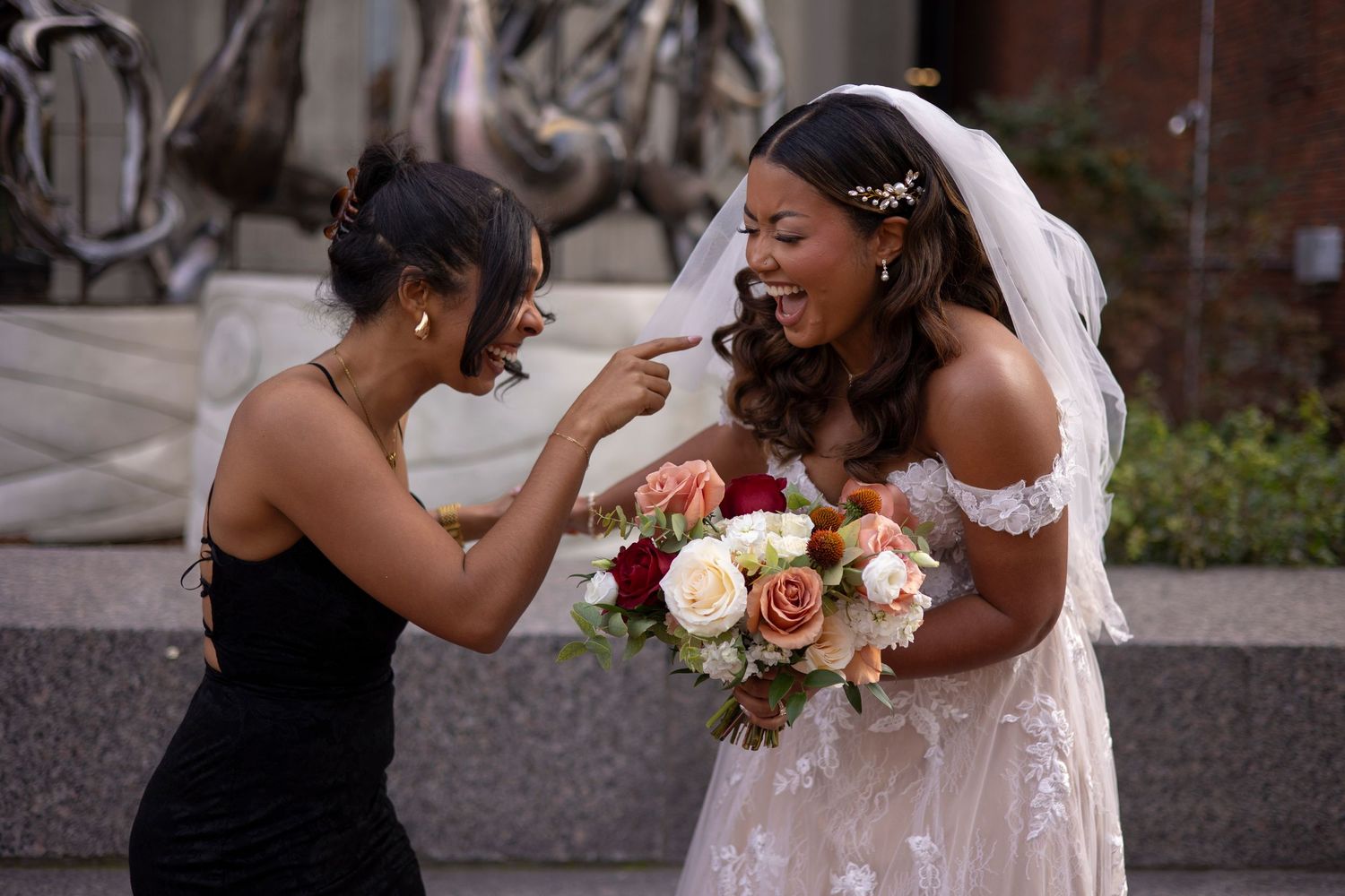 Two people in wedding attire share a joyful moment during an outdoor celebration.
