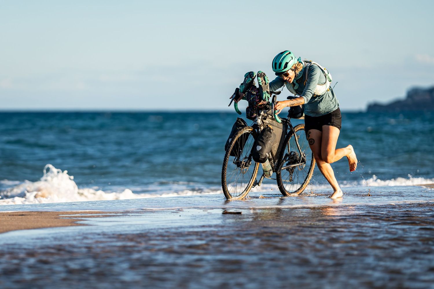 photo d'une cycliste courant dans la mer en bikepacking pour illustrer un événément bikepacking bivouak flash week-end