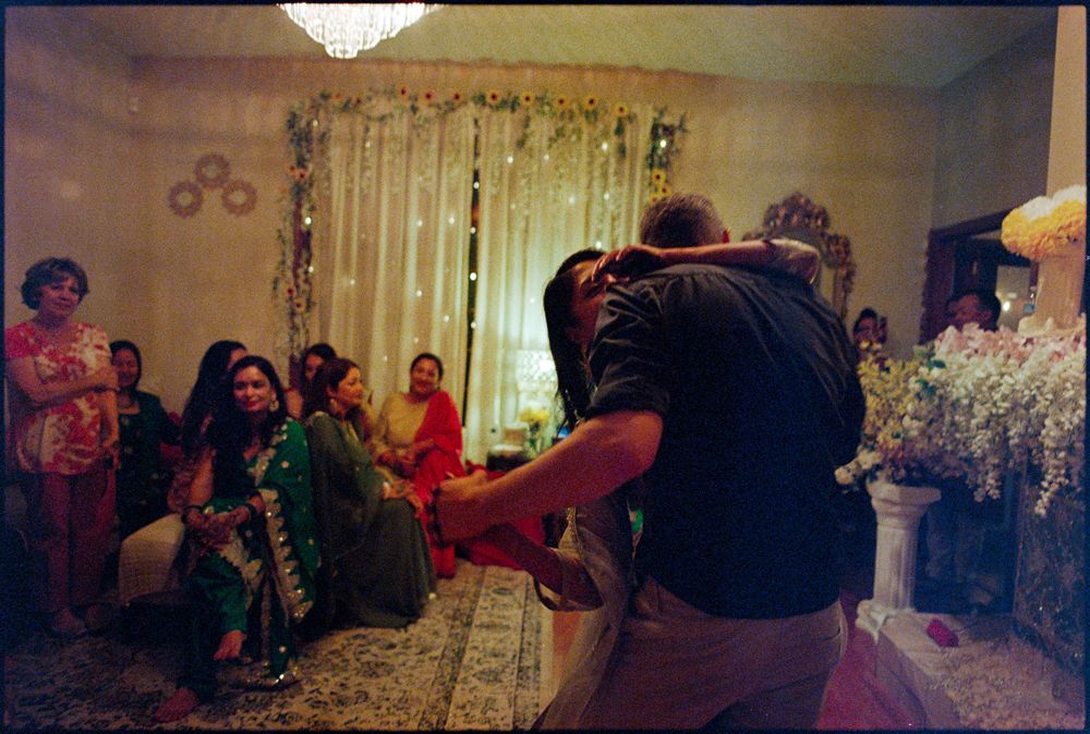 Indoor cultural celebration with women in traditional attire watching a ceremony in a decorated room.