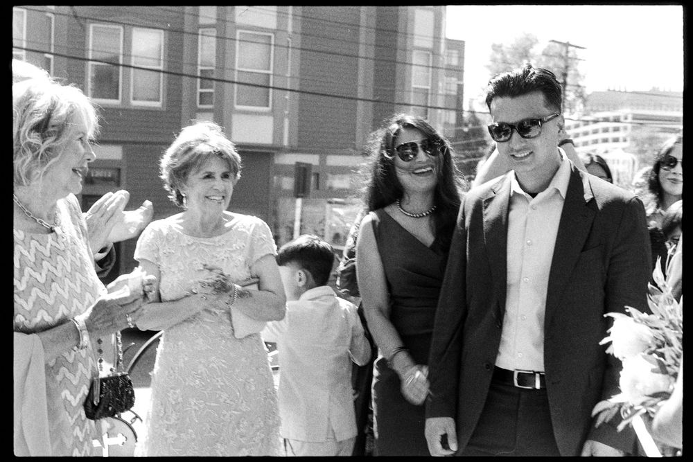 Black and white photo of wedding guests smiling and walking outdoors after ceremony celebration.