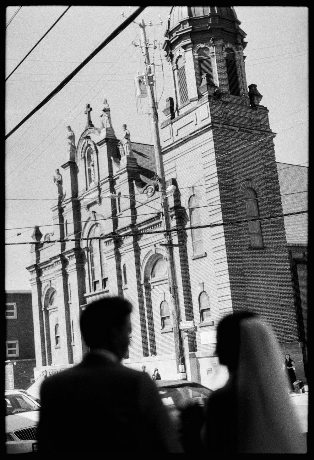 Black and white silhouette of bride and groom standing before grand ornate church facade.