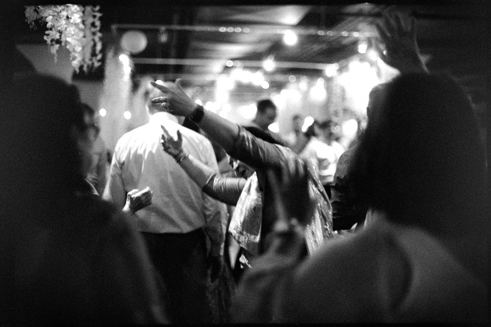 Black and white photo of guests dancing and celebrating at a lively wedding reception party.