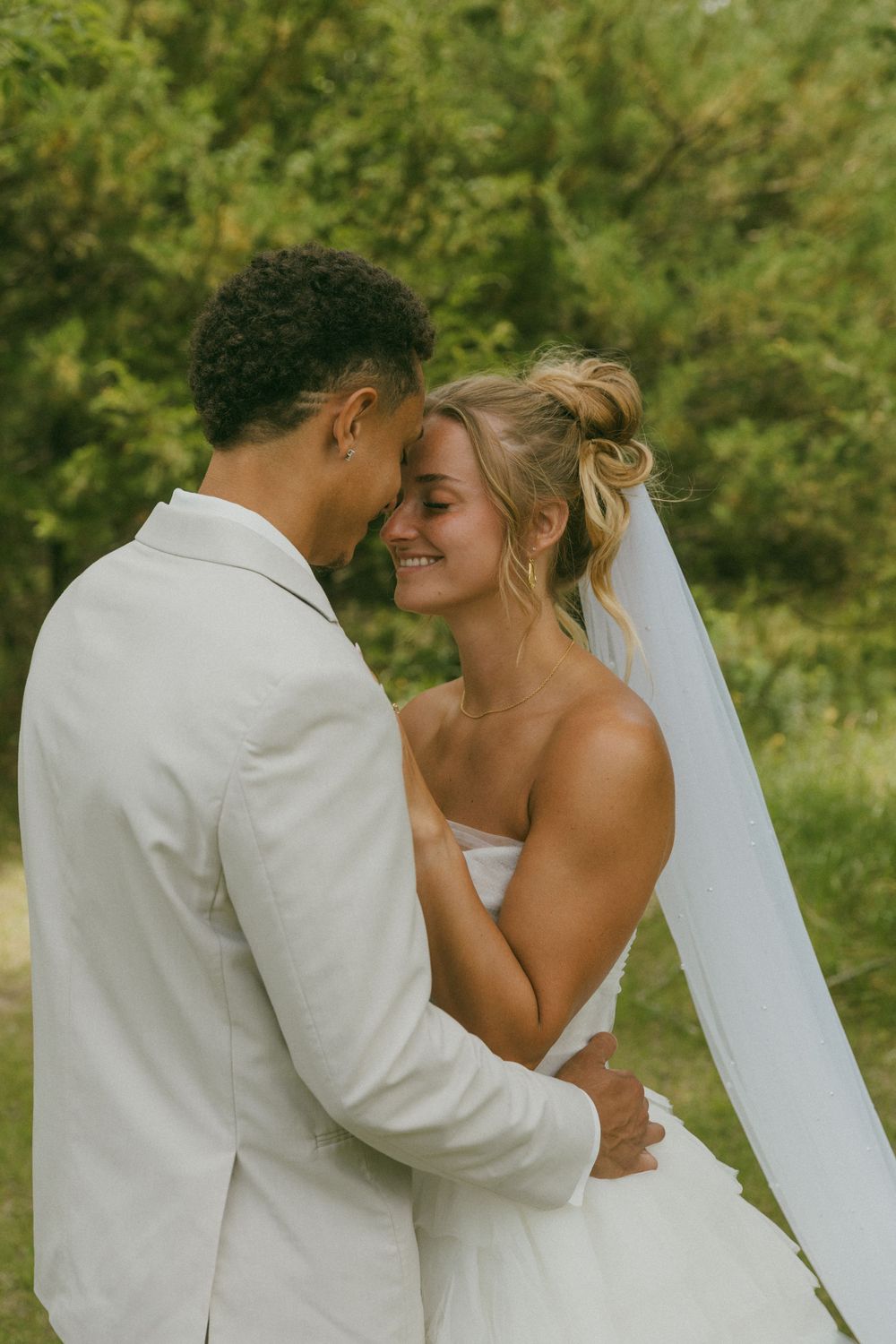 A tender moment between newlyweds sharing an intimate embrace outdoors.
