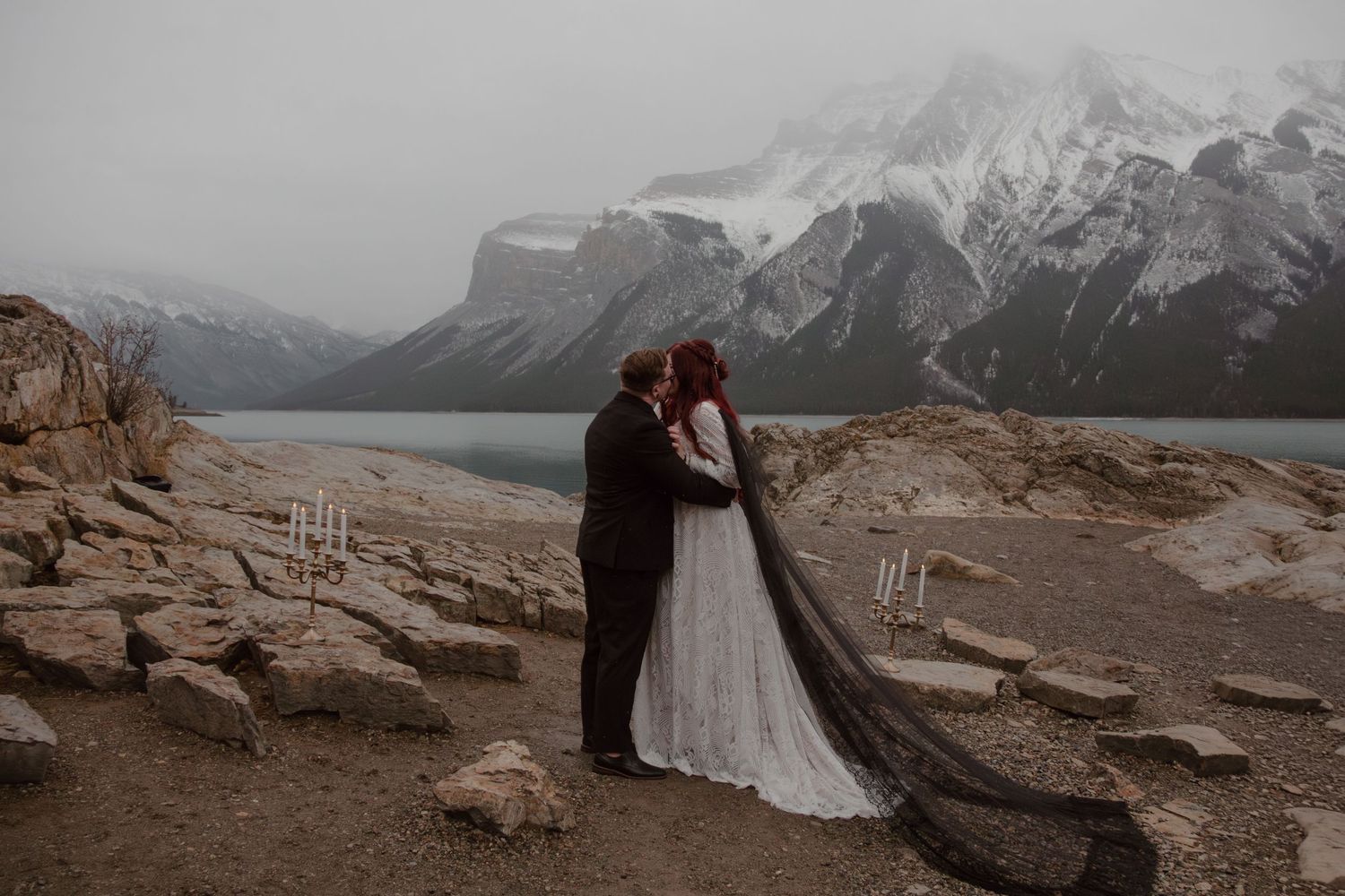 Portrait of the bride and groom kissing in front of breathtaking mountains and lake in Banff, Alberta.