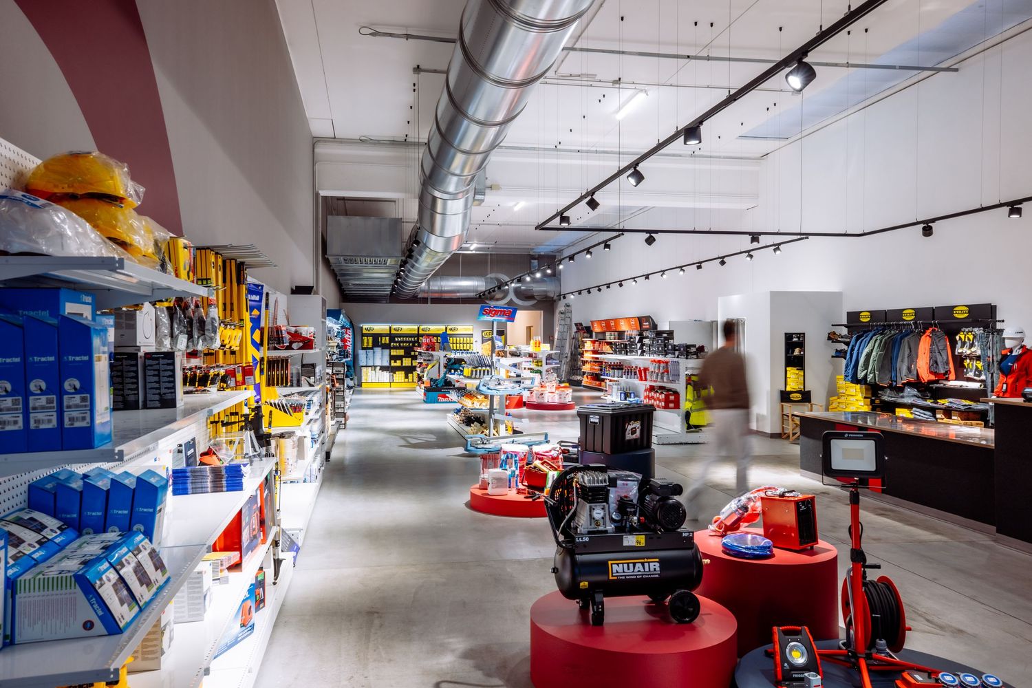 Interior view of a modern sneaker store with colorful displays, red pedestals and track lighting in a retail space.