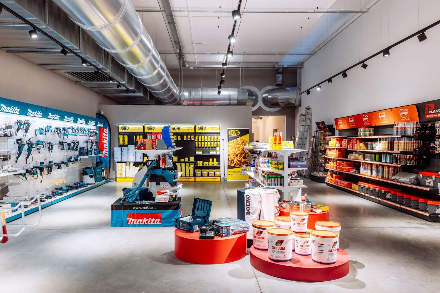 Modern hardware store interior with track lighting and organized product displays along white walls.