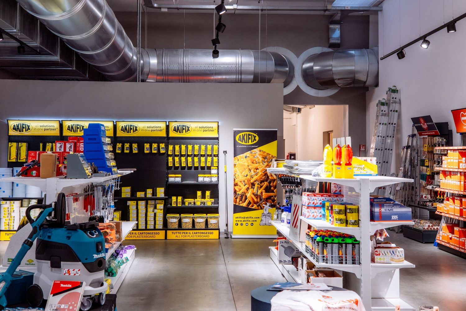 Modern convenience store interior with exposed industrial ceiling, stocked shelves and bright retail displays.