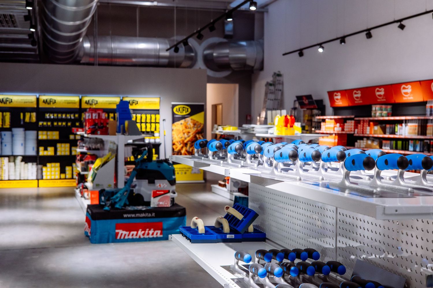 Professional hardware store interior showing organized shelves of power tools and equipment with track lighting.