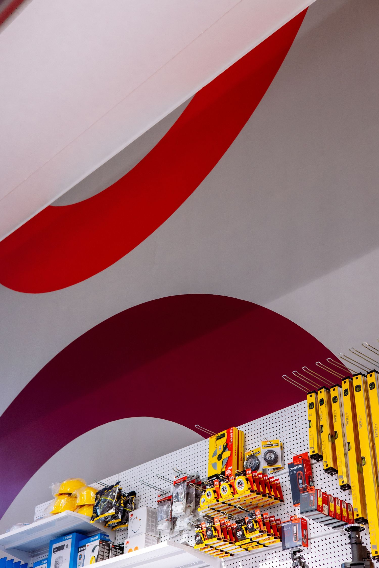 A red and white curved architectural element or design feature creates a dynamic visual pattern against a light background.