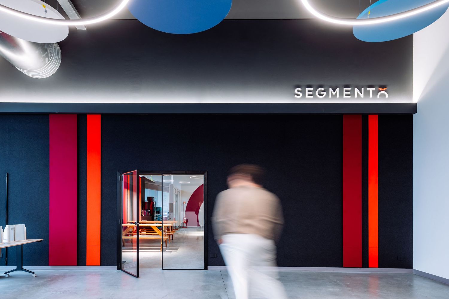 Modern office interior with black and red accent walls features sleek glass partitions and minimalist design elements.