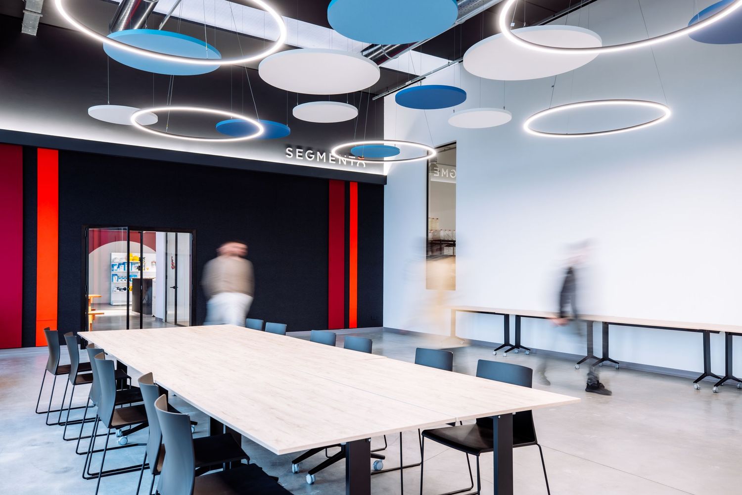 Contemporary meeting space with circular ceiling lights and long white conference table.