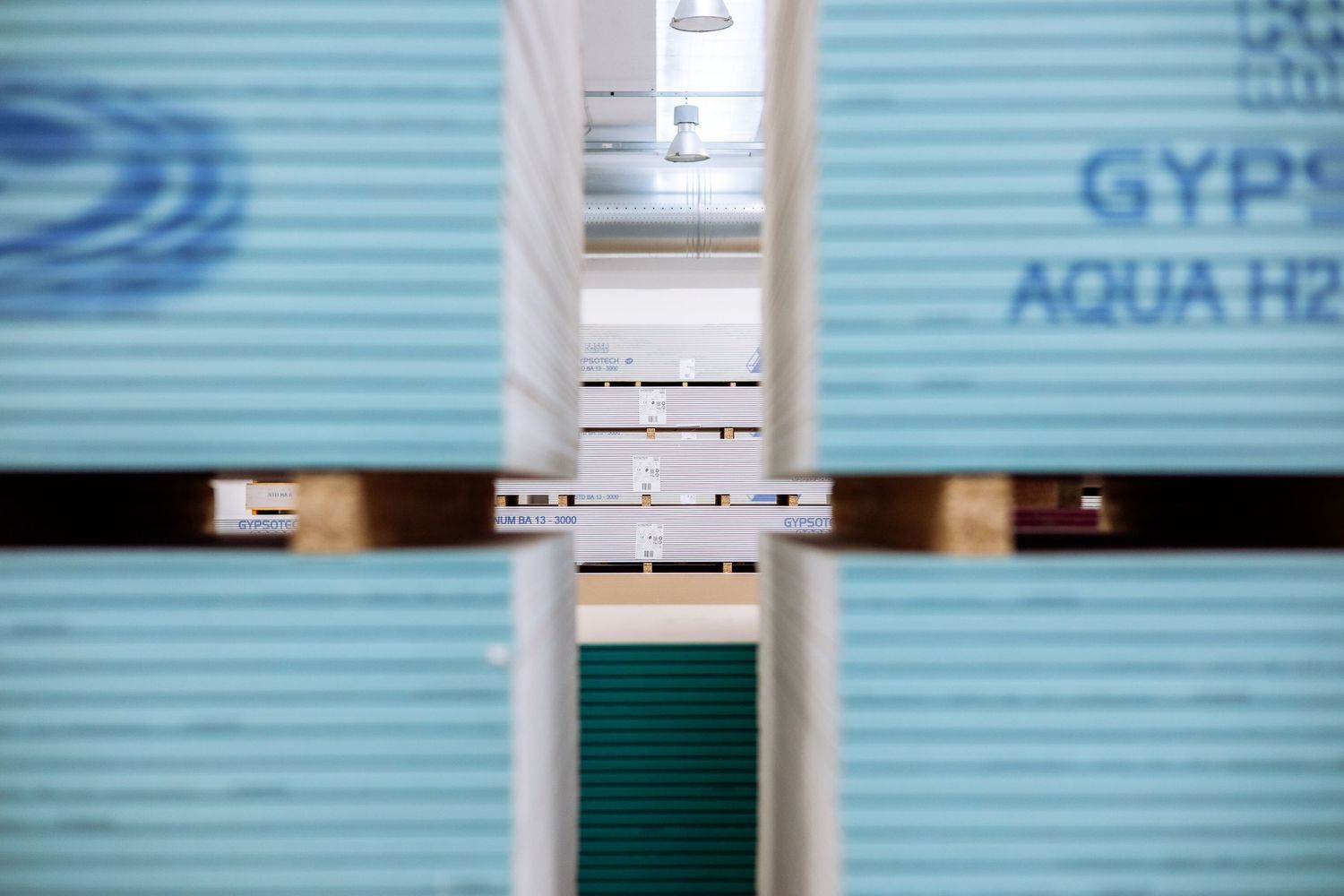 Close-up view of stacked blue and green drywall sheets with AQUA text visible through metal framing.
