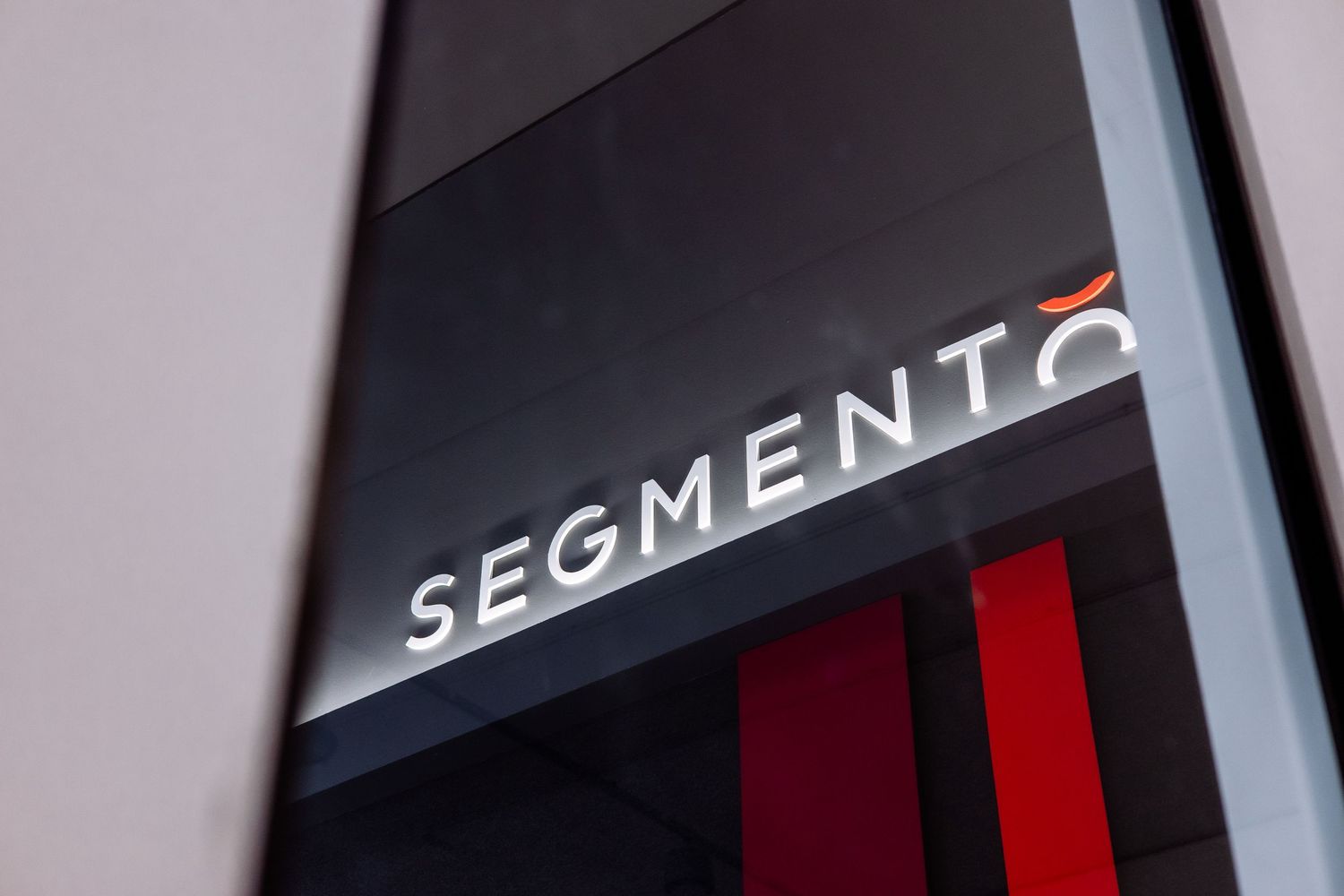 Red and white illuminated signs mounted on a dark wall create a modern retail display.