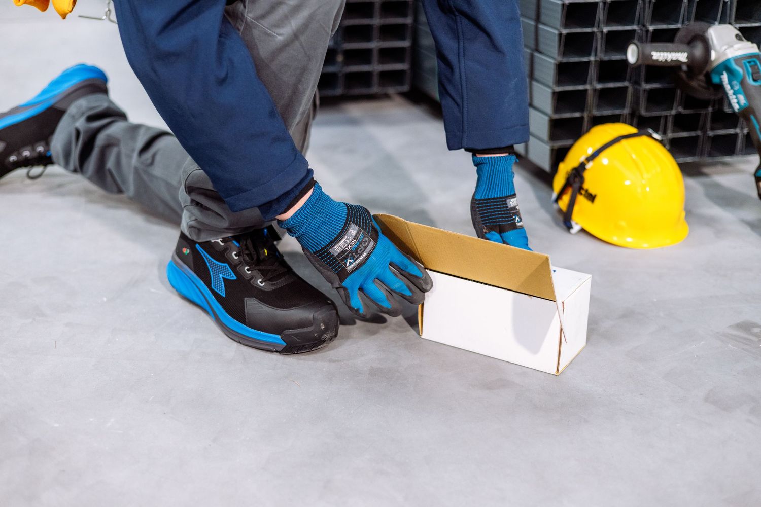 Worker examining metal channel beams stacked in an industrial warehouse environment.