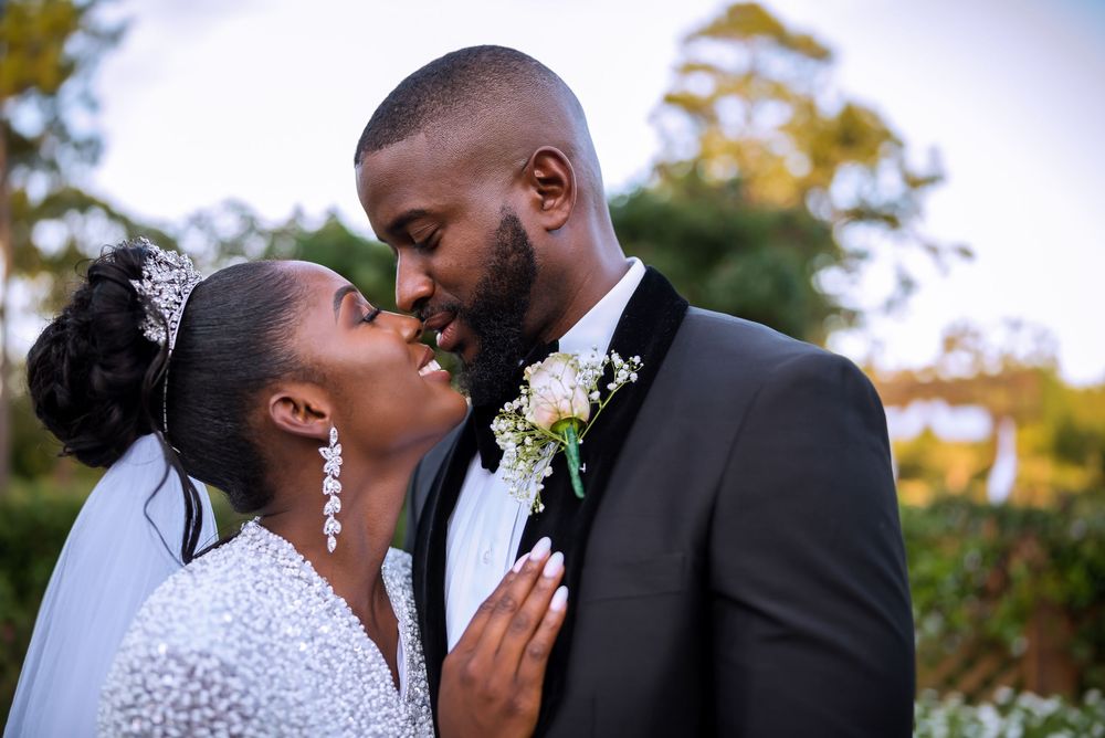 A tender moment between newlyweds outdoors with beautiful fall foliage in the background.