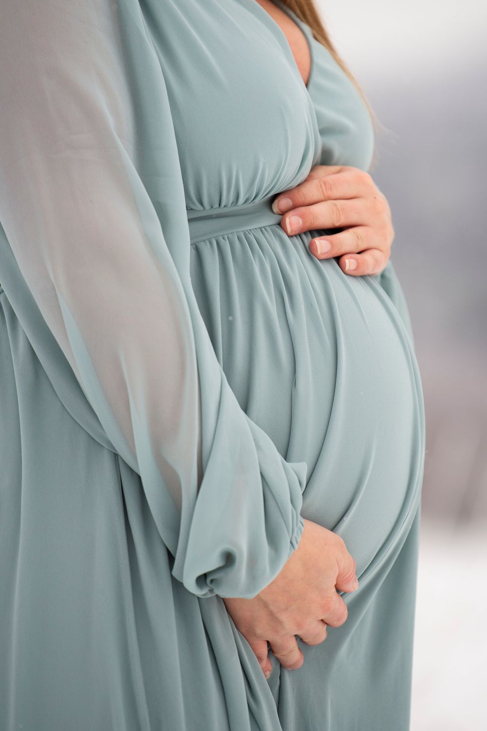 Close-up view of a light blue maternity dress with flowing sheer sleeves and gathered waistline details.