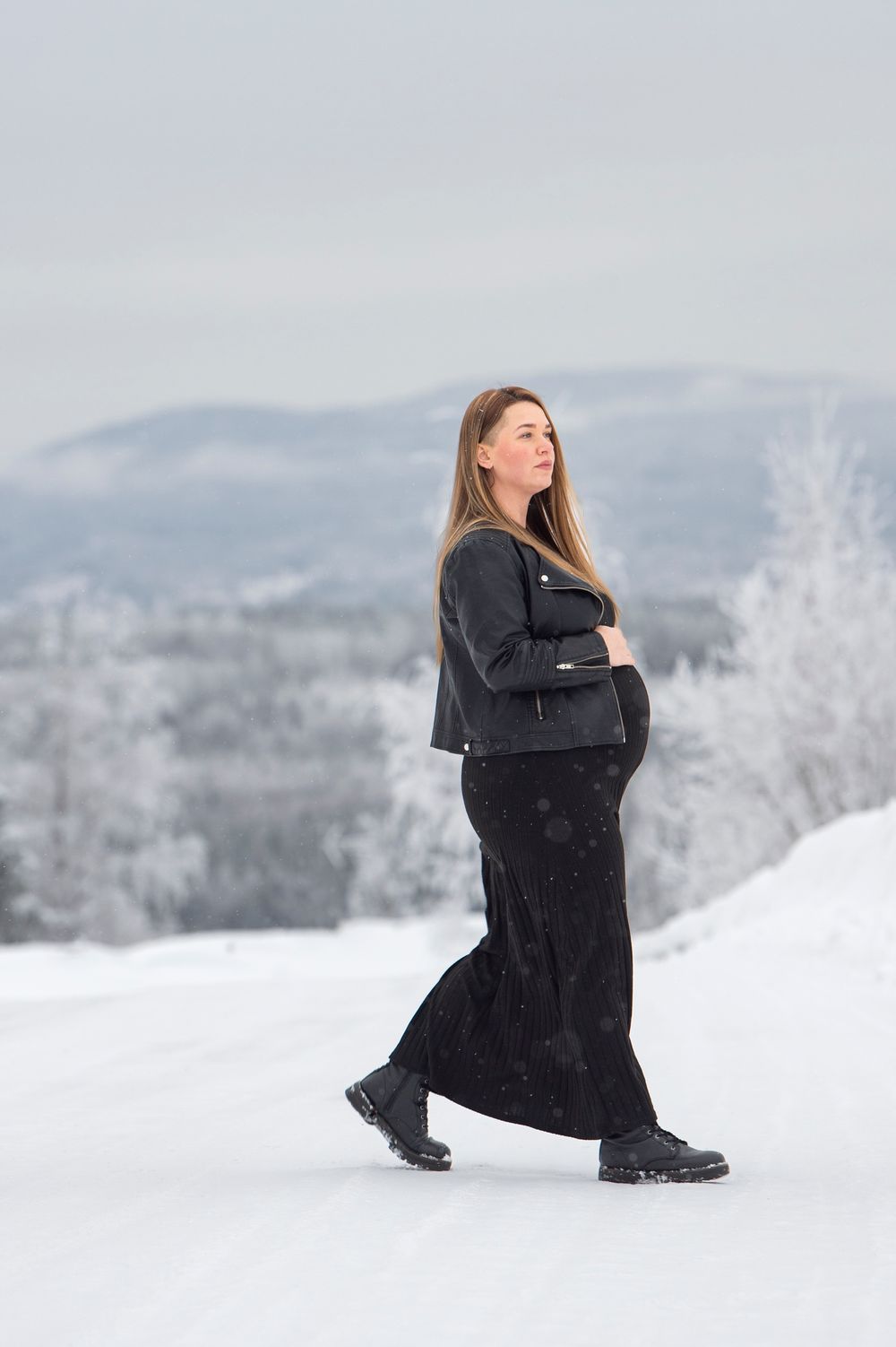 Figure in flowing black dress creates dramatic poses in a serene snow-covered mountain setting.