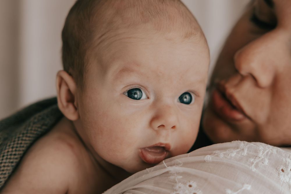 A series of close-up photos showing a baby with bright blue eyes and rosy cheeks in different poses.