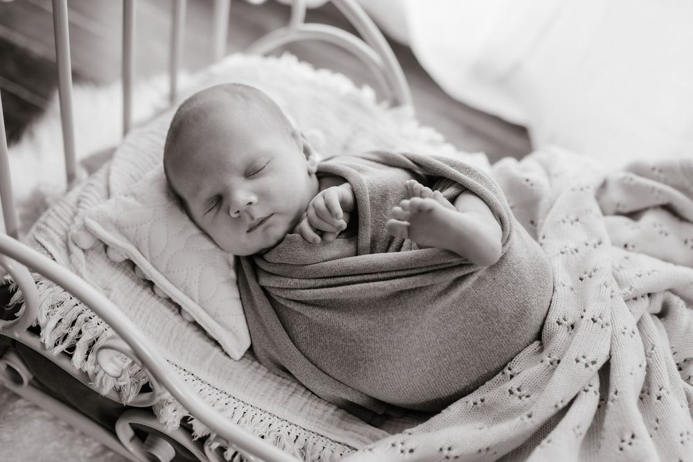 Black and white collage of newborn baby photography with soft wraps and blankets.
