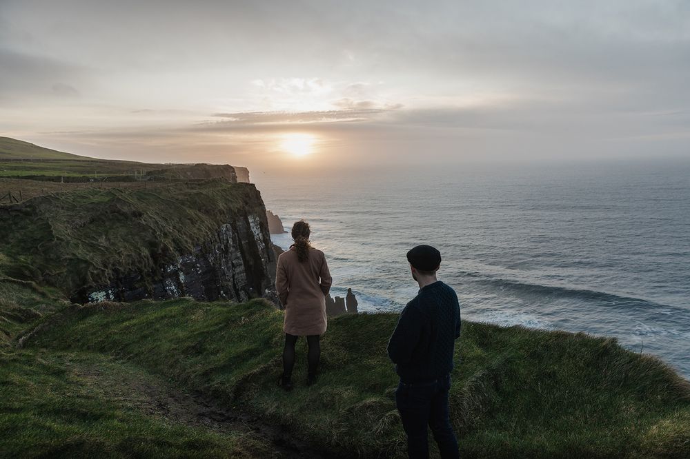 Cinematic sunset couple portraits overlooking dramatic coastal cliffs in Ireland
