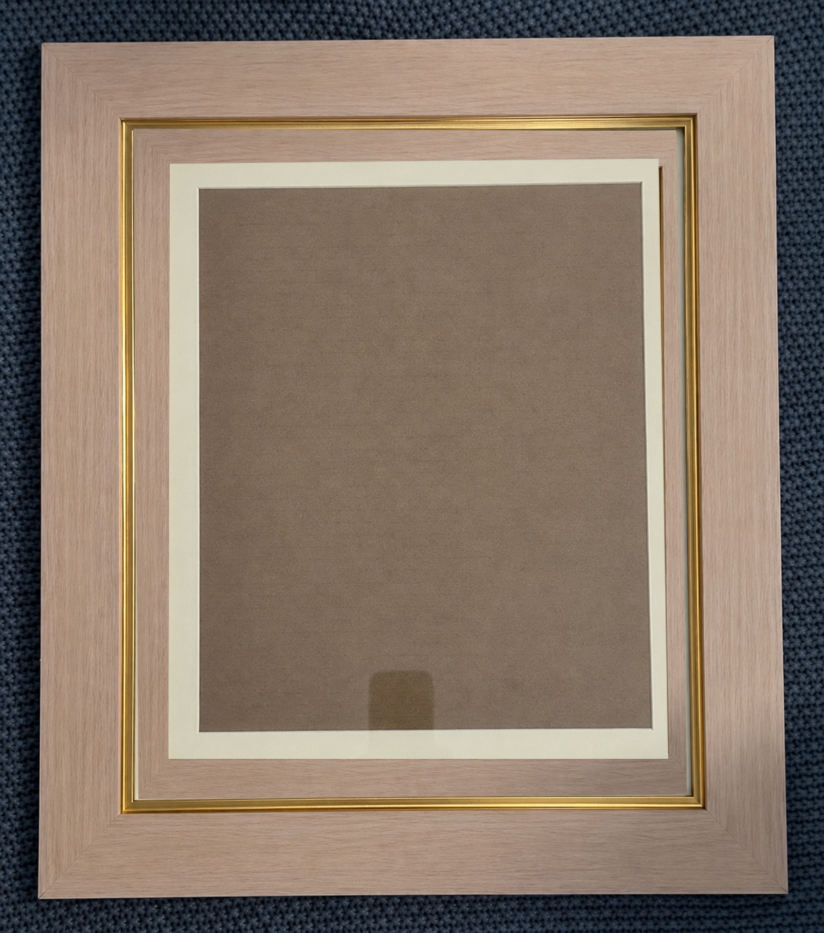 Pink and gold picture frame with cream mat and brown backing, displayed on a dark blue textured surface.