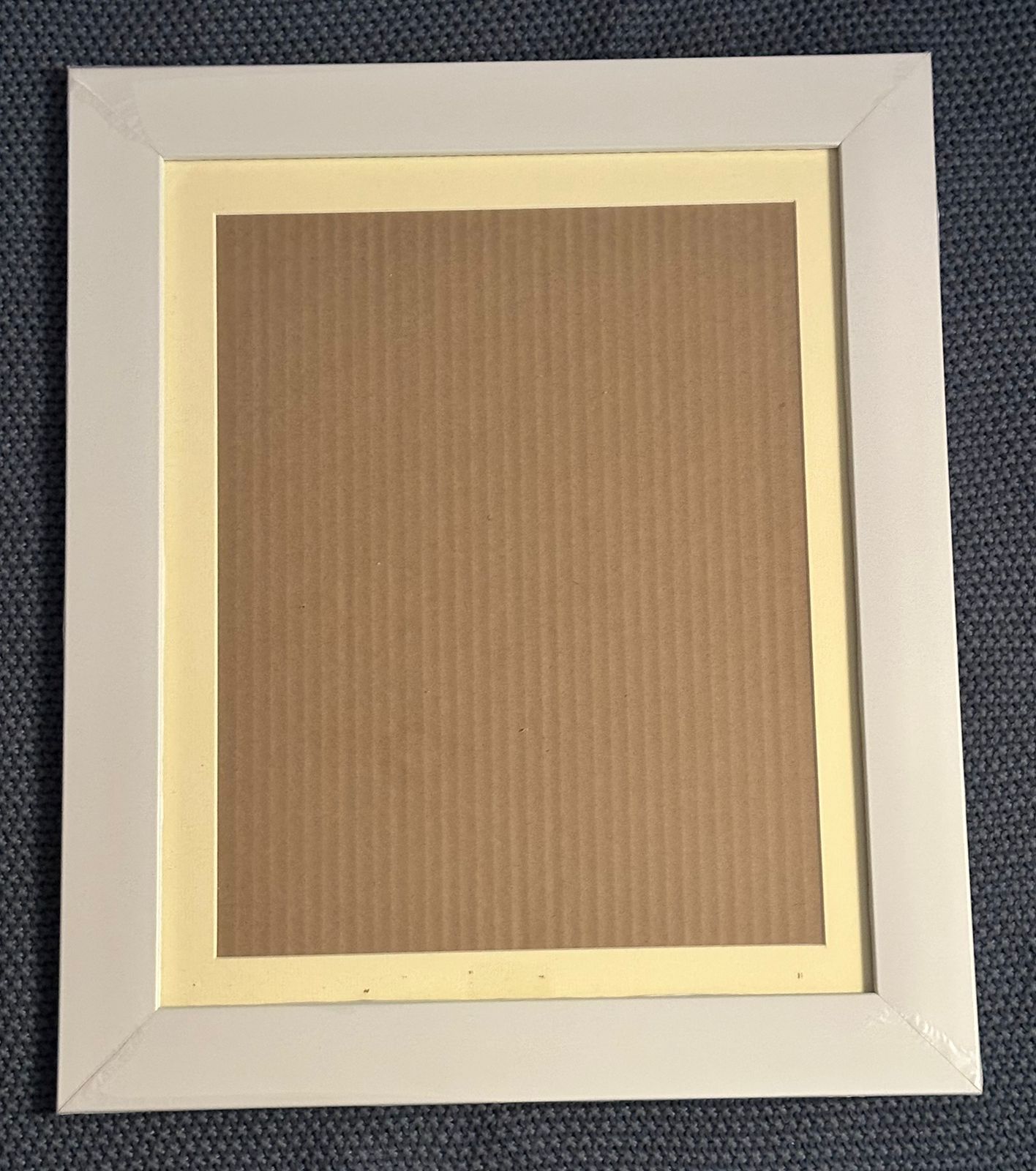 Empty wooden picture frames with cream-colored matting arranged in a row against a dark blue textured background.