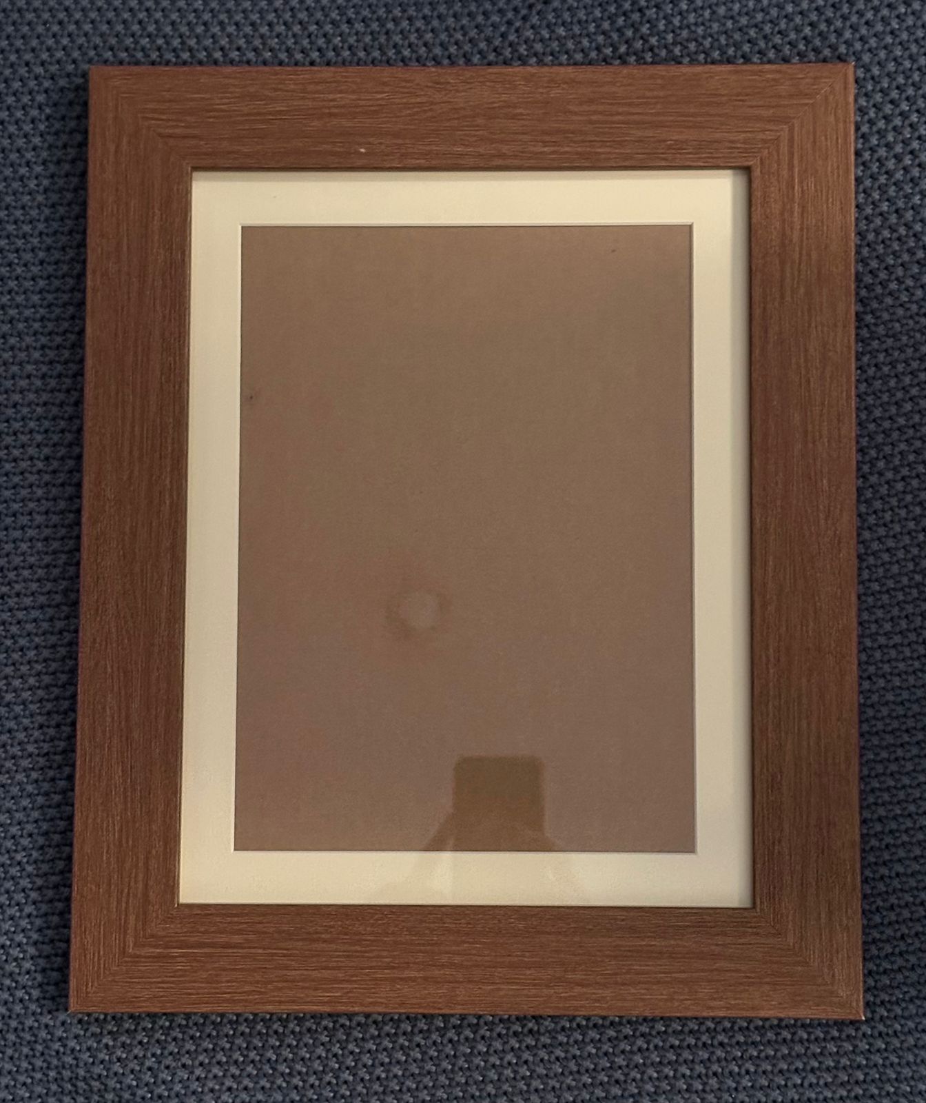 Three vintage-style wooden picture frames with matting displayed against a dark blue textured fabric background.