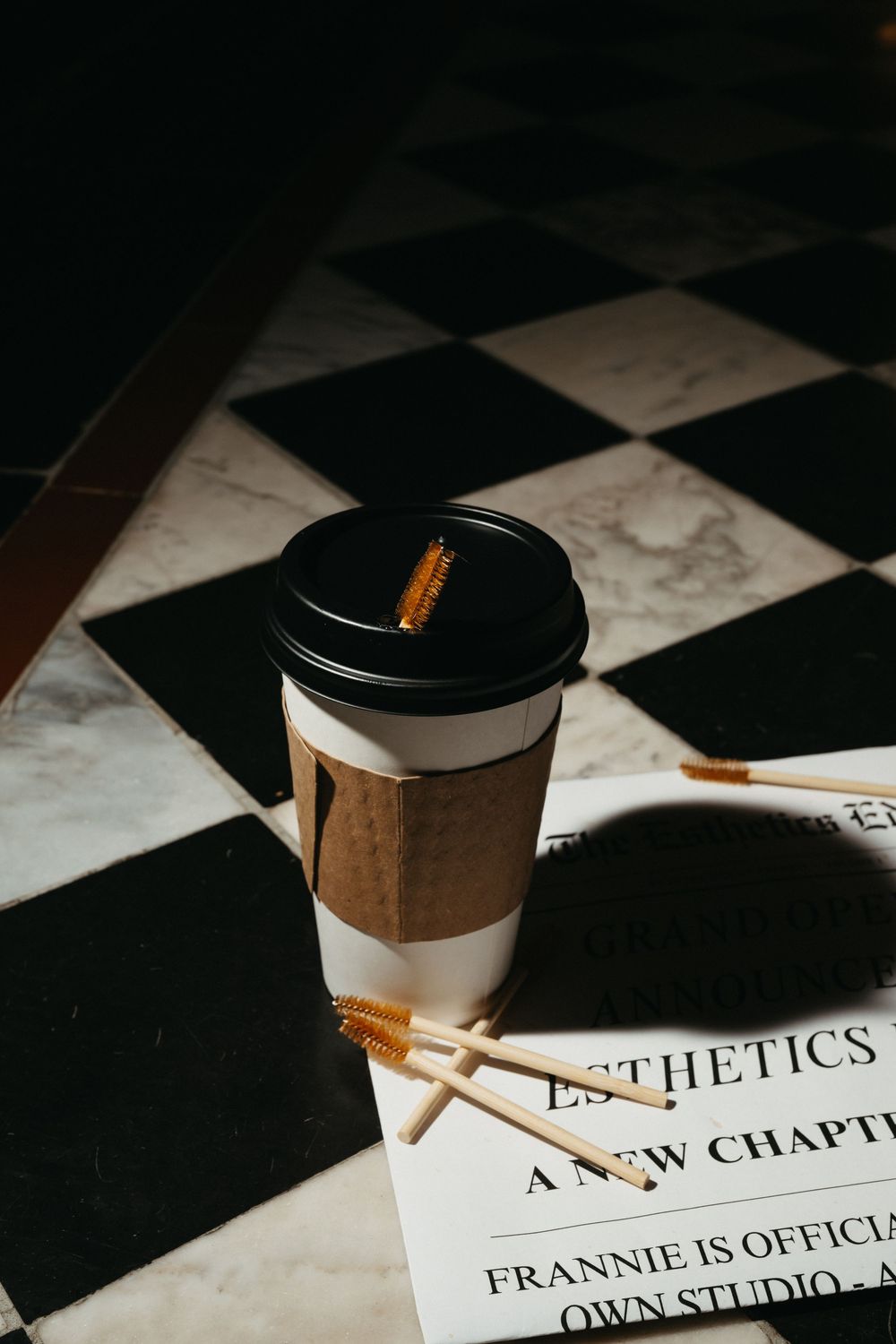 Coffee cups and papers on black and white checkered surface with text visible.