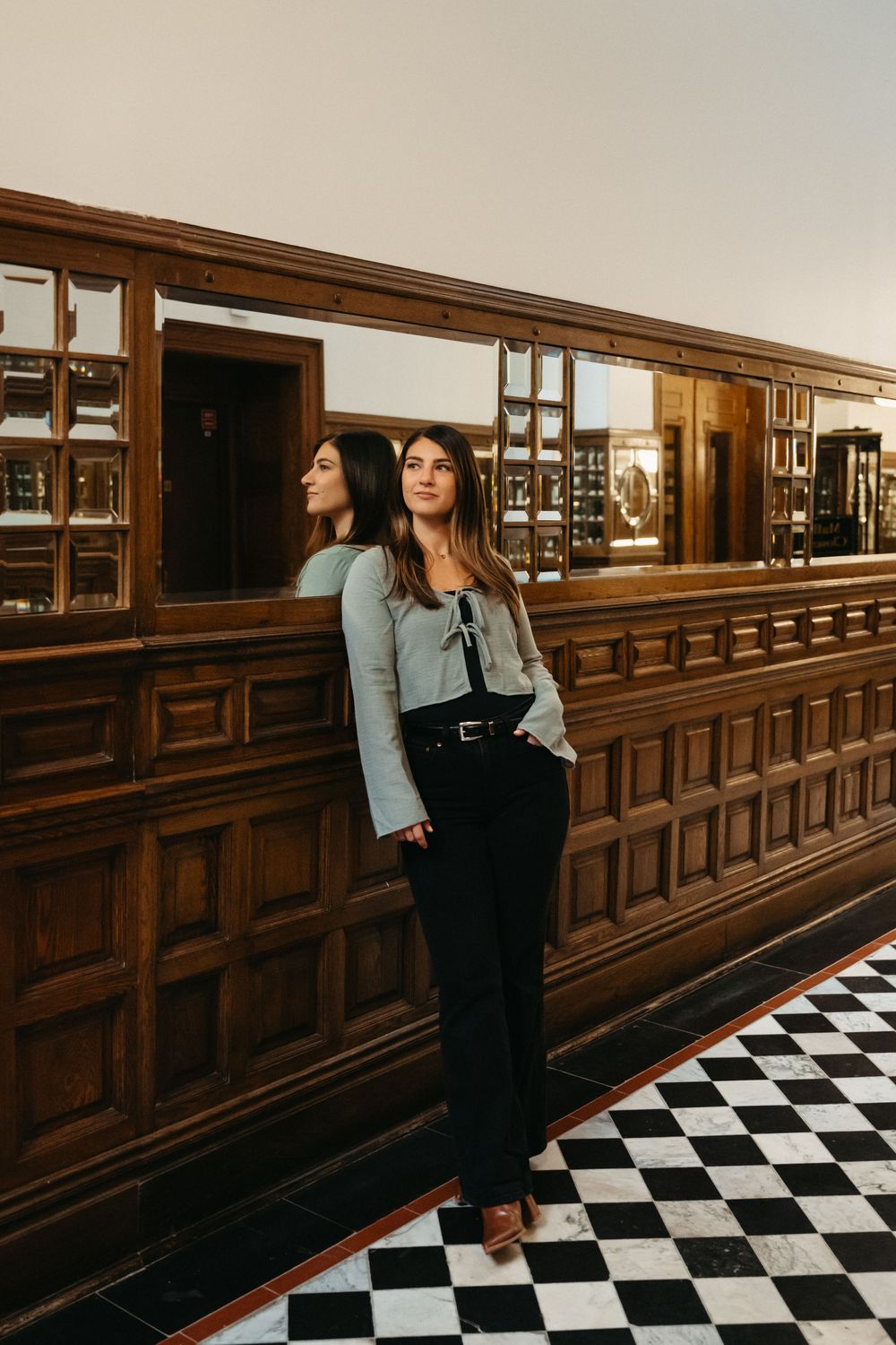Interior hallway with wooden paneling and checkered floor showing dramatic lighting and reflections.