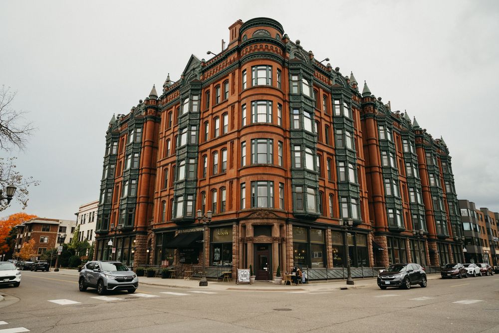 Panoramic view of a historic red brick corner building with Victorian architecture and bay windows.