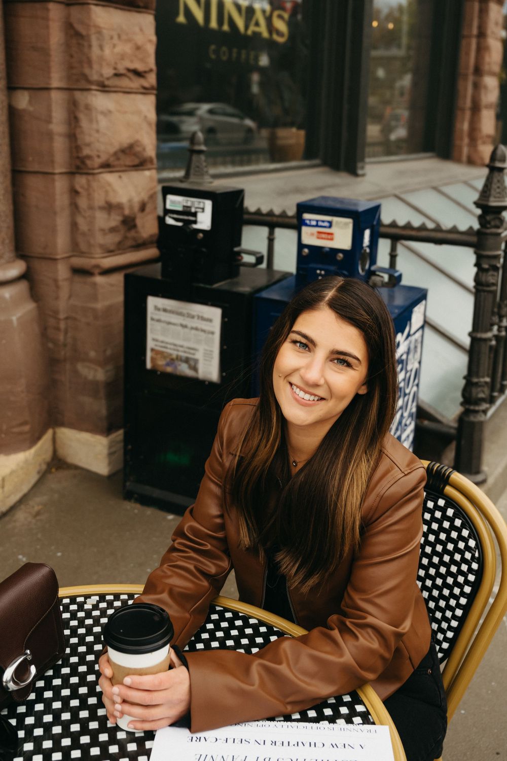 Person sitting at outdoor cafe table with coffee and polka dot chair.