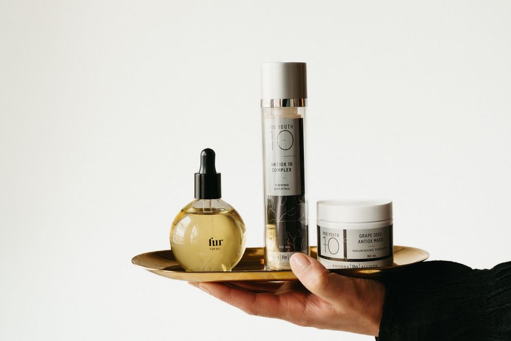 Collection of luxury skincare products arranged on reflective surface with clean aesthetic.