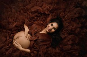 A person poses against dark brown silk fabric in a dramatic fashion photography series.