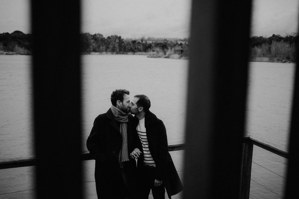 A romantic black and white photo of a couple sharing an intimate moment by a lake.