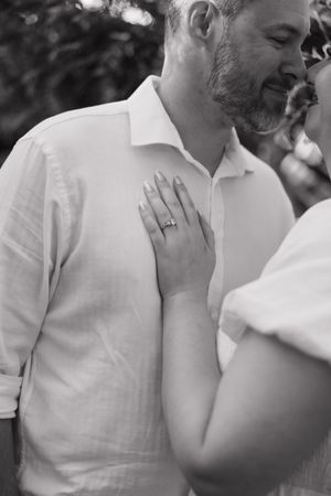 A tender black and white moment showing a gentle touch and wedding ring during an intimate outdoor photoshoot.