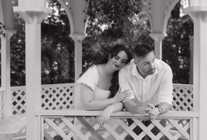 Family members gather on a white porch with lattice railings, sitting together and enjoying conversation outdoors.