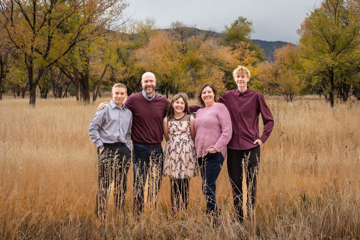 A group of people walking together through a golden autumn field with mountains in the background. Bear Creek Park, Colorado Springs