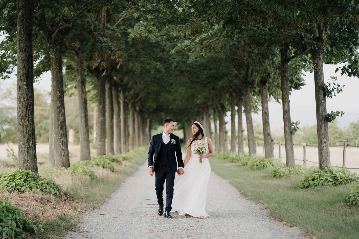 Sposi che camminano in un viale alberato durante il servizio fotografico di matrimonio in Liguria
